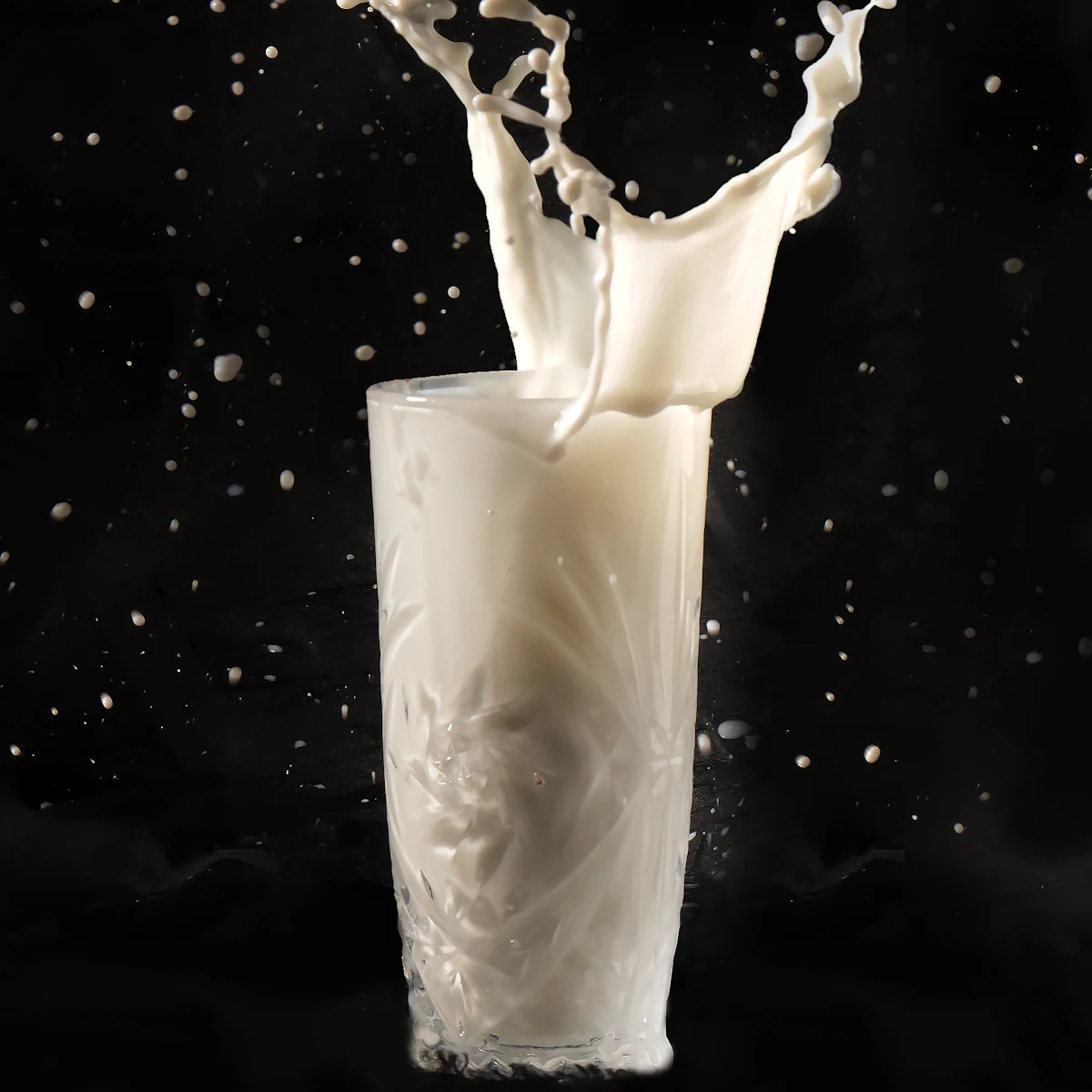Fresh milk splashing out of a tall glass